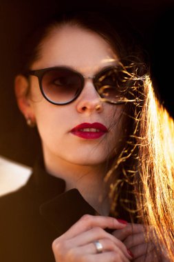 Genç kadın siyah ceket ve siyah şapka poz.