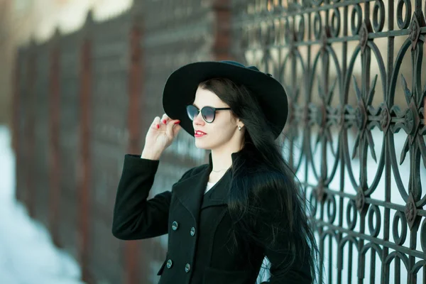 Giovane donna in posa in cappotto nero e cappello nero . — Foto Stock