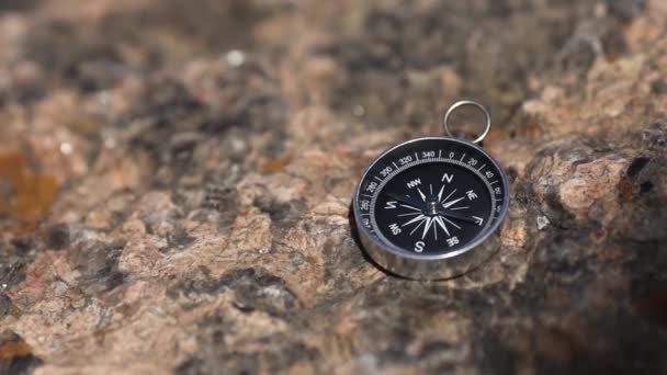 Магнитный компас с черным циферблатом на диком камне, покрытом мхом . — стоковое видео