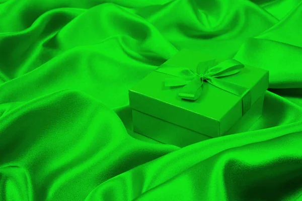Green gift box on green silk. Greeting card bakcground. — Stock Photo, Image