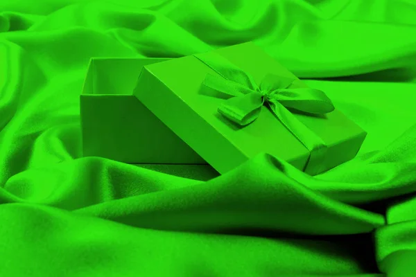 Open green gift box on luxurious green silk — Stock Photo, Image