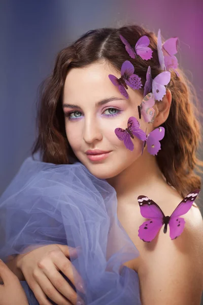Hermosa joven con mariposa artificial en el pelo rizado. —  Fotos de Stock