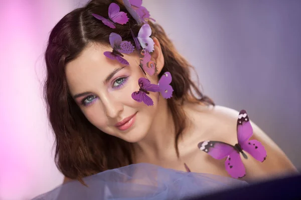 Hermosa joven con mariposa artificial en el pelo rizado. —  Fotos de Stock