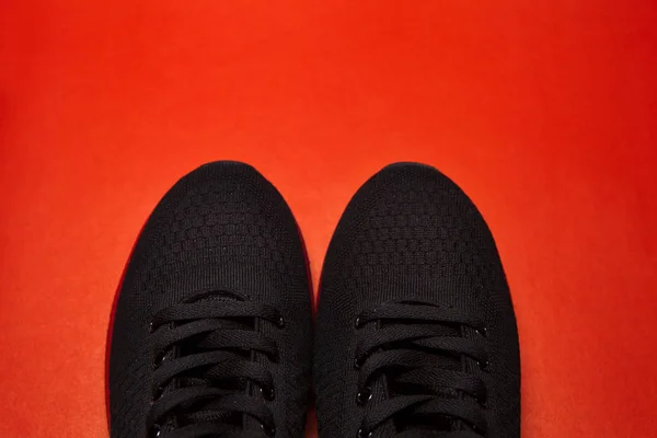 Zapatillas deportivas negras aisladas sobre fondo rojo — Foto de Stock