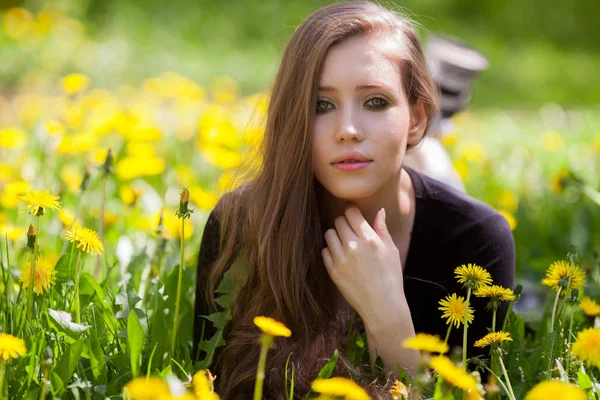 Beeld van mooie vrouw liggend op paardebloemen veld. — Stockfoto