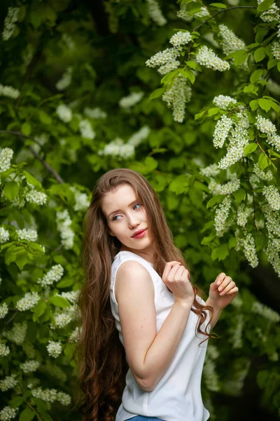 Portret van een vrouw op een achtergrond van bloeiende vogel kers. — Stockfoto