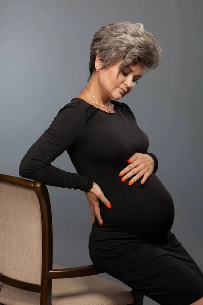 Portrait of loving pregnant woman looking at belly while posing — Stock Photo, Image