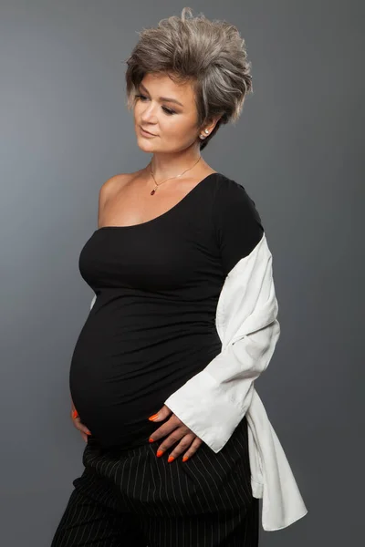 Портрет любящей беременной женщины, смотрящей в камеру во время позирования — стоковое фото