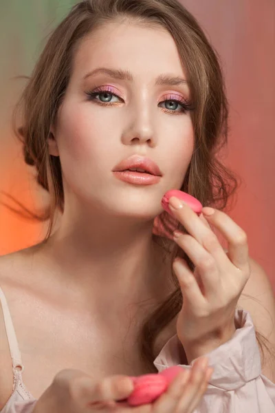 Skönhet mode modell flicka med delikat makeup och manikyr tar rosa makaroner — Stockfoto