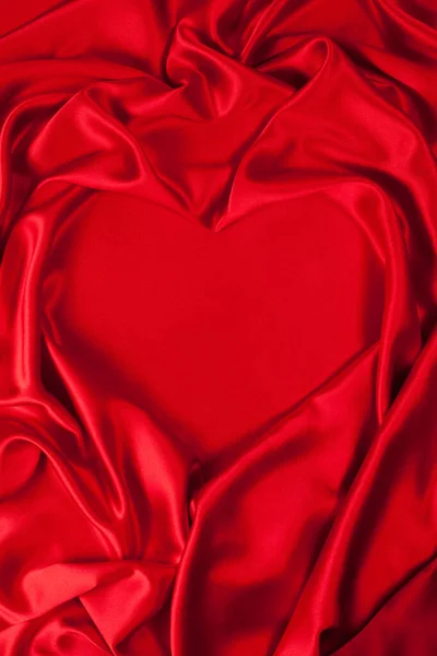 Forma de corazón, fondo de tela de seda roja, pliegues de tela. —  Fotos de Stock