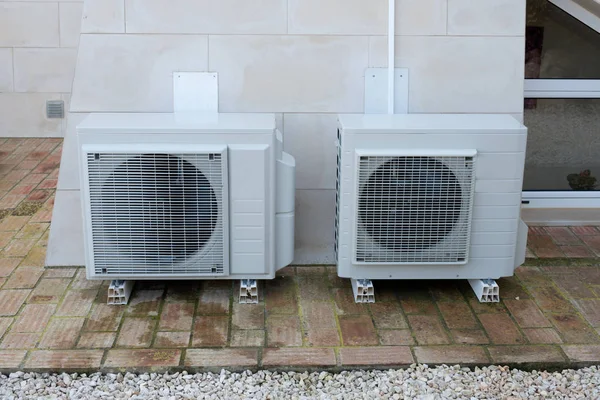 Two air conditioning units outside a house