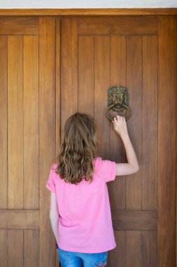 young girl knocking on front door of house using metal door knocker clipart