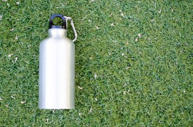 Yeşil çim arka plan üzerinde yeniden kullanılabilir su şişesi