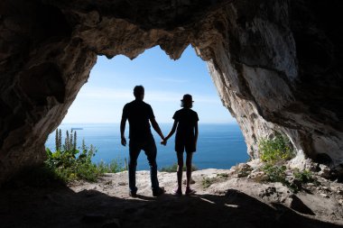 Mağaranın girişinde duran turist siluetleri.