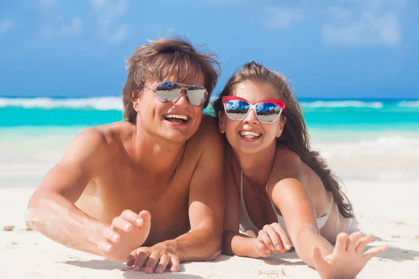 Feliz joven pareja mintiendo y divirtiéndose en una playa tropical —  Fotos de Stock