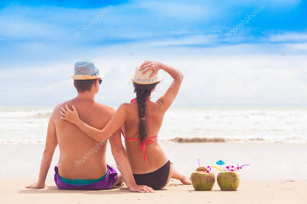 happy young couple sitting and having fun on a tropical beach