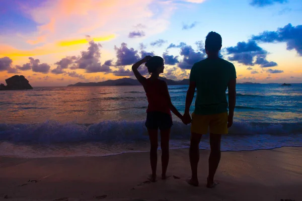 Gün batımı silueti plajda birbirine aşık genç bir çiftin kucaklaşması. — Stok fotoğraf