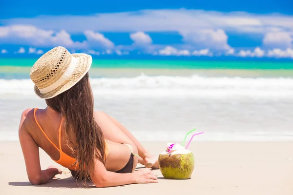 Long haired woman in bikini and straw hat with fresh coconut juice on tropical beach — Stock Photo, Image