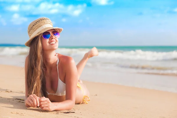 Vrouw in bikini en stro hoed liggend op tropisch strand — Stockfoto