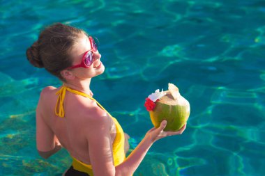 Güzel genç kadın güneş gözlüğü Hindistan cevizi lüks havuzu elinde kokteyl ile