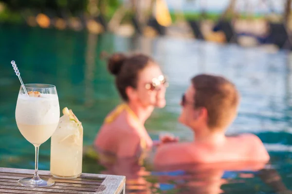 Joven pareja bonita disfrutando de la noche de verano con cócteles en la piscina de lujo — Foto de Stock