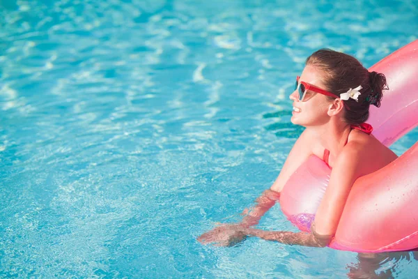 pembe kauçuk şişme halka yüzme havuzunda yüzen ve eğlenmek güzel kadın