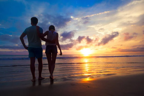 Pôr do sol silhueta de jovem casal apaixonado abraçando na praia — Fotografia de Stock