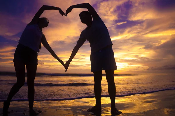 Ηλιοβασίλεμα σιλουέτα του νεαρό ζευγάρι στην αγάπη, κρατώντας τα χέρια στην παραλία — Φωτογραφία Αρχείου