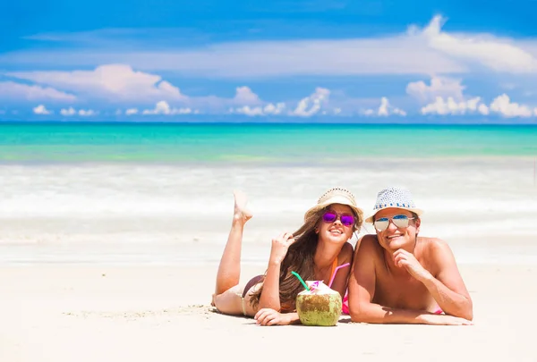 Jeune couple se relaxant à la plage tropicale avec des cocktails de noix de coco frais — Photo