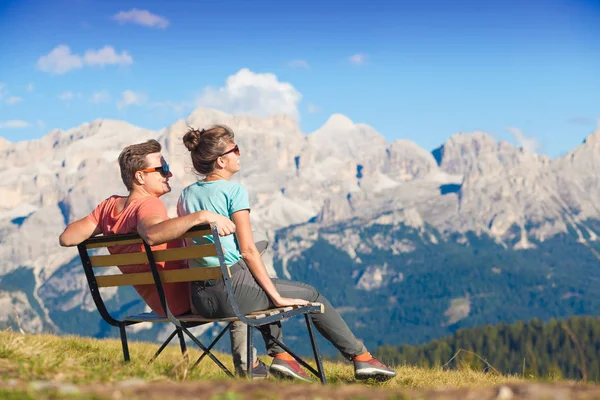 Vandrere med rygsække siddende på bænken på toppen af en bakke og nyde bjergene udsigt. Dolomiti og Alta Badia - Stock-foto