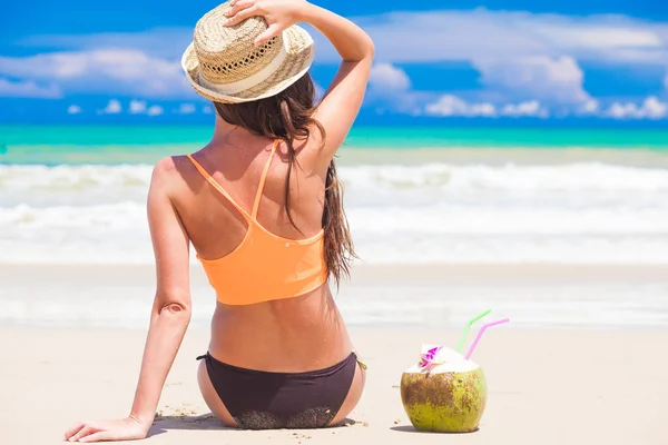 Lång haired kvinna i bikini och halm hat med färsk kokosnöt juice på tropical beach — Stockfoto