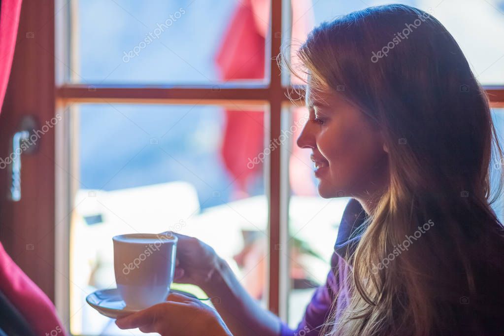 Half face portrait of young woman relaxing and drinking coffee at Passo Gardena. Dolomites, Italy