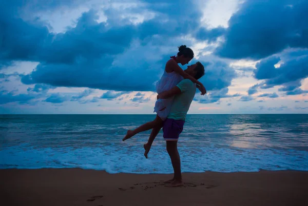 Zonsondergang silhouet van jong paar in liefde knuffelen op het strand — Stockfoto