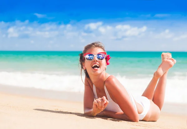 Mulher de biquíni e óculos de sol vermelhos deitada na praia tropical — Fotografia de Stock