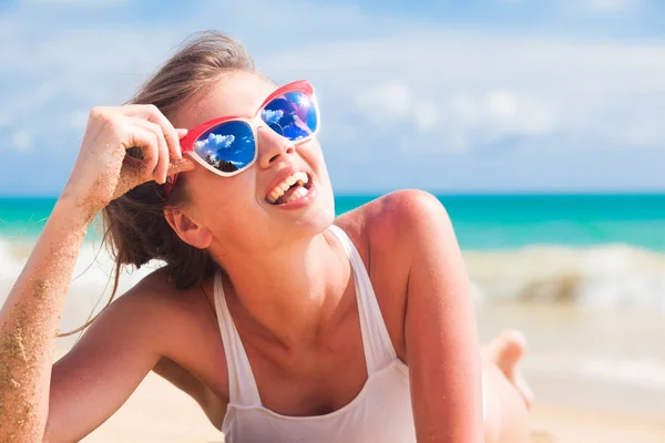 Vrouw in bikini en rood zonnebril liggend op tropisch strand — Stockfoto