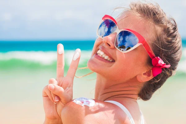 Nahaufnahme einer jungen Frau mit Sonnenbrille, die Sonnencreme auf die Schulter legt — Stockfoto