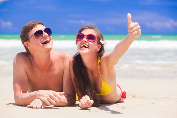 portrait of happy young couple lying and having fun on a tropical beach