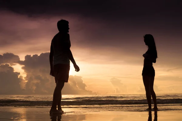 Fiatal pár szerelmes a tengerparton napnyugtakor sziluettje. naplemente — Stock Fotó