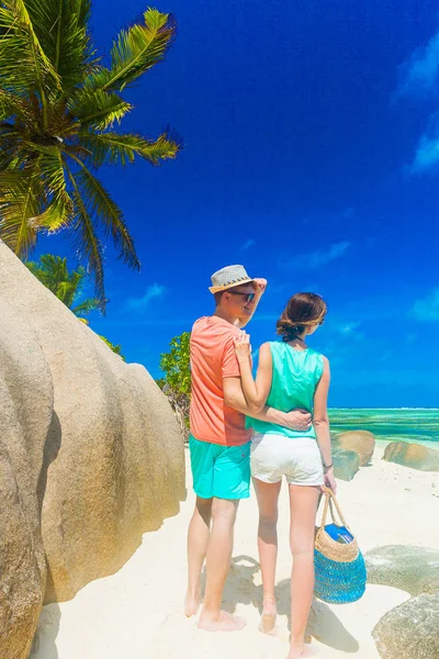 Casal em roupas brilhantes em uma praia tropical em La Digue, Seychelles . — Fotografia de Stock