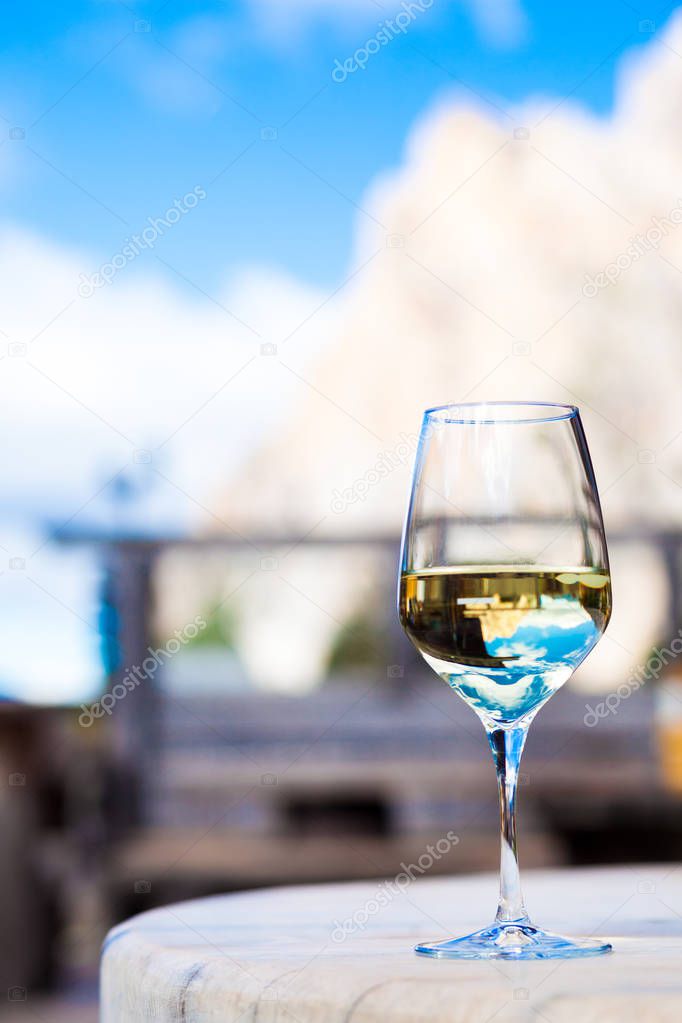 Glass of chilled white wine on a rocky mountain background. Hiking in Dolomites, Italy