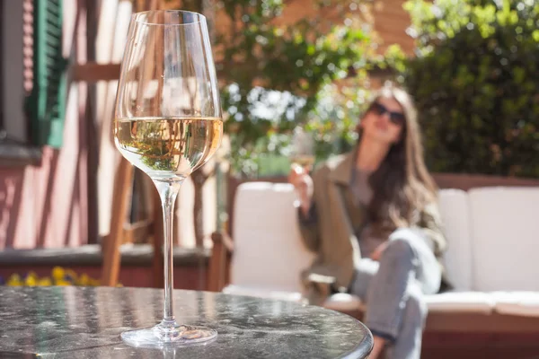 Glas gekoelde witte wijn op tafel over jonge vrouw en Tuscany achtergrondkleur — Stockfoto
