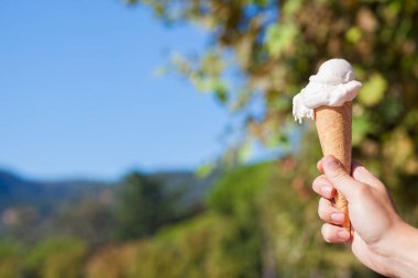 Bir doğa arka plan üzerinde dondurma konisi. elinde dondurma tutan adam.