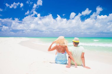 Romantik seyahat balayı tatil yaz tatili romantizm beyaz kum plajda oturan plaj çift. Genç mutlu aşıklar, Cayo Largo, Küba