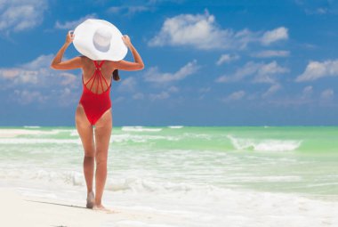 Beyaz Karayip plajında dinlenen bikini ve hasır şapkalı genç kadın