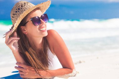 Beyaz Karayip plajında dinlenen bikini ve hasır şapkalı genç kadın