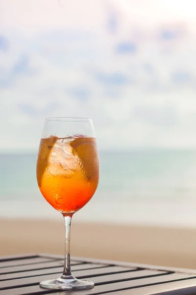 Heerlijke ijskoude aperol spritz geserveerd op een kleine houten tafel op een warm tropisch strand in de zomer zon — Stockfoto