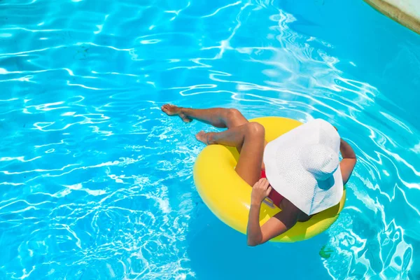 Jovem mulher bonita está relaxando na piscina com anel de borracha . — Fotografia de Stock