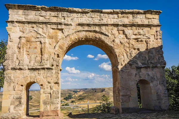 Close-up of Roman arch and back the village of Medinaceli. Soria Spain.