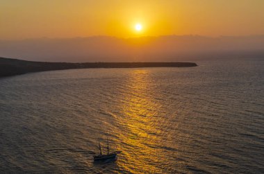 Santorini, Yunanistan - 9 Ekim 2014: Oia Köyü nde günbatımı. Santorini Adası civarında sırasında gün batımına yelken çift direk Yelkenli.