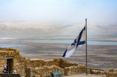 İsrail bayrak sallayarak Masada ve arka planda Harabeleri üzerinde Judean desert ve Dead Sea.